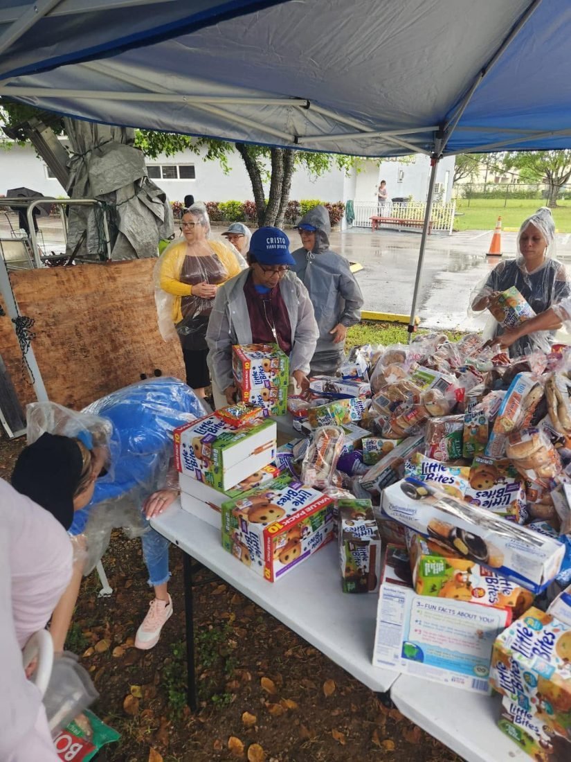 Voluntarios organizando pan y comestibles sobre las mesas de entrega